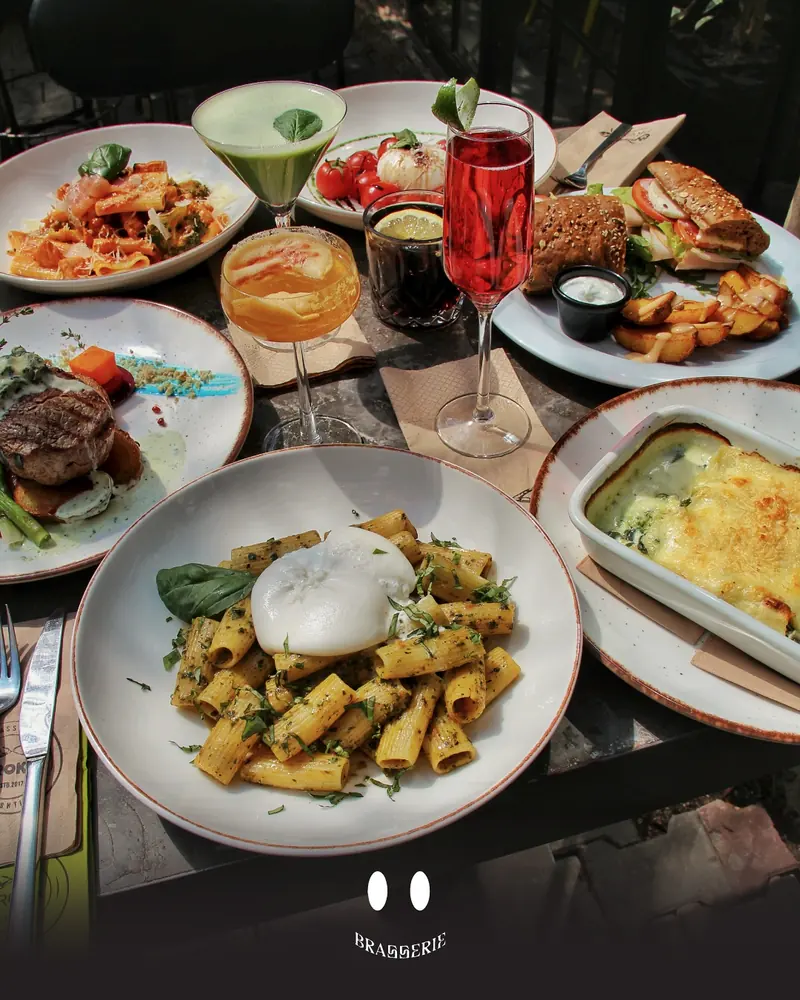 Tavolinë e mbushur me pasta, biftek, sanduiç dhe kokteje